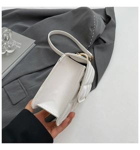 Detailed side view of white quilted faux leather handbag with elegant gold hardware
