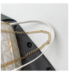 Detail of white quilted handbag with golden chain strap and precise stitching work