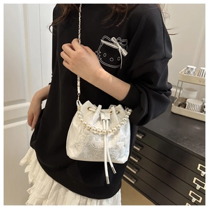 Detail of white lace bucket bag with pearl handle and delicate floral embroidery textures