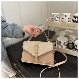 Detail view of woven leather flap and gold hardware on an apricot crossbody bag