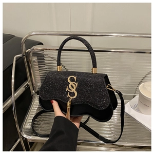 Détail du sac carré noir à paillettes avec logo S doré et pampille métallique chic