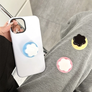 Three colorful flower-shaped phone grip sockets shown on a white smartphone case
