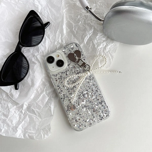 Detail of iPhone case with silver glitter, pearl bow charm, and heart-shaped metal ring