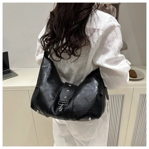 Detail view of black matte leather tote bag with silver star studs on a female model