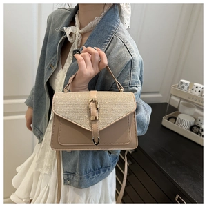 Detail of beige shoulder bag with glitter textured flap and vintage gold metal lock