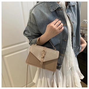 Detail of light brown leather crossbody bag featuring glitter flap and gold metal buckle
