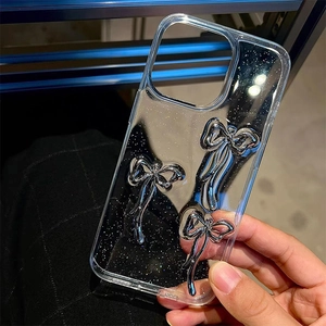 Detail of clear glitter phone case with silver 3D bows for iPhone 16 Pro Max