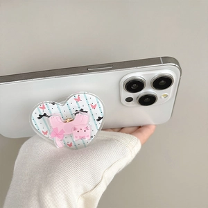 Pink cartoon cat heart-shaped griptok on white smartphone held against a clean wall