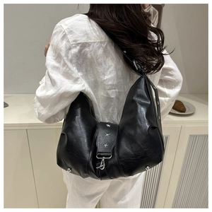 Close-up of black leather crescent bag featuring silver star rivets and metal hook detail