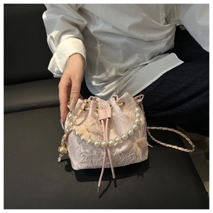 Detailed view of a pink lace bucket bag featuring pearl handle and butterfly accents