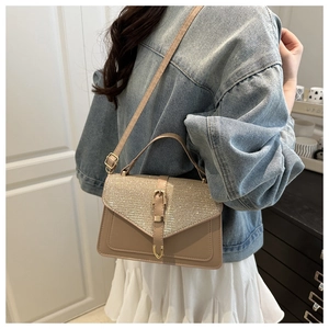 Detail of glittery silver flap beige crossbody bag shown worn with a denim jacket