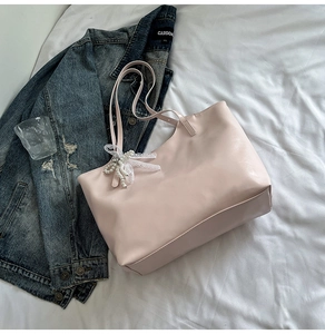 Dettaglio della borsa tote rosa con ciondolo a fiocco in pizzo perlato e texture liscia
