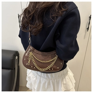Detail of dark brown crescent bag with faux crocodile texture and golden chains