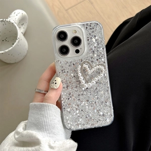 Detail of glittery phone case with pearl heart and bow charm for iPhone 16 Pro Max