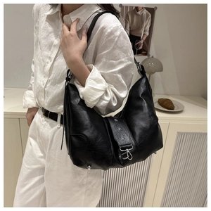 Detail of black crescent shoulder bag featuring silver star rivets and premium leather texture
