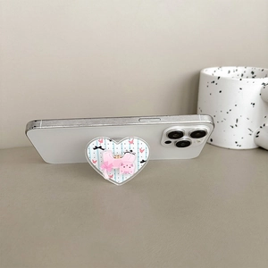 Detail of heart-shaped phone grip with pink cat illustration on a white smartphone