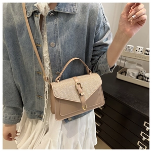 Detail of crossbody bag with shimmer flap texture and golden metallic buckle