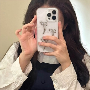 Λεπτομέρεια θήκης iPhone με 3D ασημένιους φιόγκους σε λευκή μαργαριταρένια βάση
