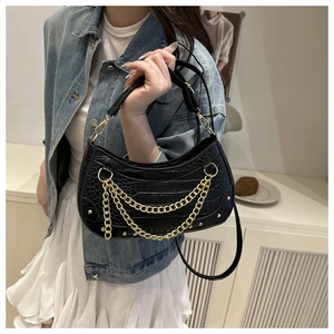 Detail of black croc-embossed half-moon bag with gold chains and metal studs
