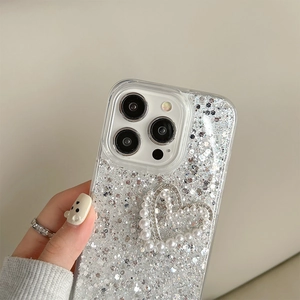 Detailed close-up of glitter iPhone case featuring pearl heart and diamond-encrusted bow design