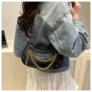 Detail of black crocodile texture crescent bag with decorative gold metal chain strap