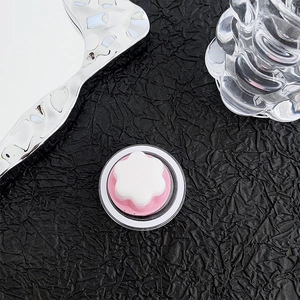 Close-up of petal-shaped magnetic phone grip in transparent container on black paper