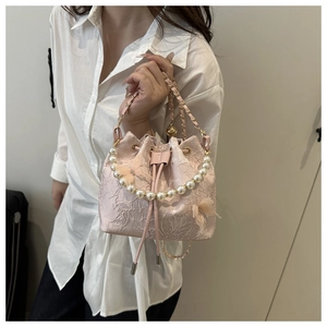 Close-up of pink bucket bag with pearl handle, 3D butterfly, and floral embroidery details