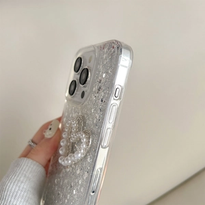 Detail of silver glitter phone case featuring a 3D pearl heart pendant for iPhone