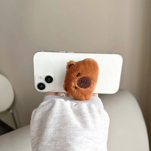 Close-up of a brown plush bear head collapsible phone grip on a white smartphone