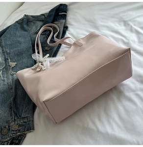 Dettaglio borsa tote rosa con fiocco in pizzo bianco e decorazione ciondolo di perle