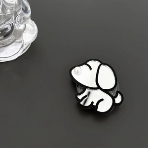 Detail shot of a mirror-finish dog phone grip with a pearl accent on a dark grey surface