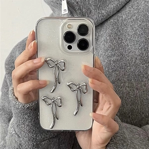 Detail of transparent glitter phone case featuring three 3D silver bow accessories