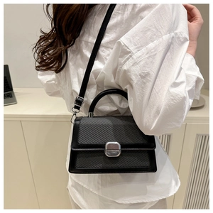 Close-up of woven crossbody bag with black leather trim and silver square lock detail