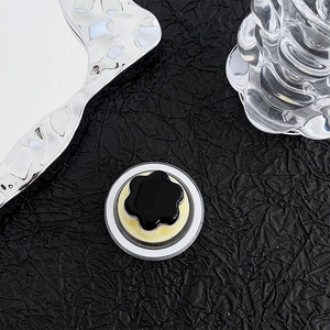 Detail of flower-shaped Magsafe grip in black and yellow on a textured backdrop