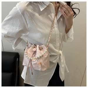 Close-up of pink lace bucket bag featuring 3D butterfly, pearl handle and gold chain
