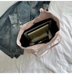 Interno spazioso della borsa tote in ecopelle rosa con libri, tablet e perle