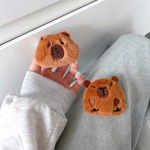 Macro detail of plush brown capybara phone stand showing soft texture and embroidery