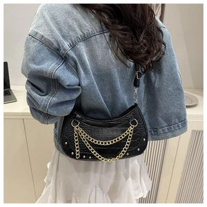 Detail of black croc-effect hobo bag with three-tier gold chains and metal studs