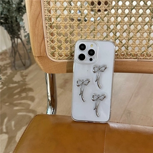Λεπτομέρεια διάφανης θήκης iPhone με τρεις ασημένιους μεταλλικούς φιόγκους σε ξύλινη καρέκλα