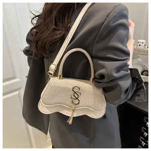 Détail du sac bandoulière crème avec bordure ondulée et logo en métal doré