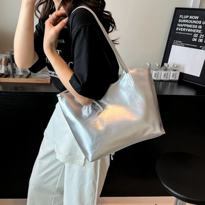 Grande borsa tote argento metallizzato con ciondolo di pizzo e perle su una modella