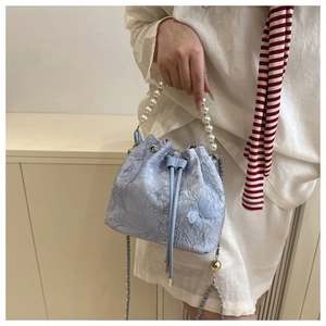 Detail of light blue lace bucket bag with 3D butterflies and elegant pearl handle