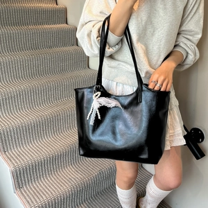 Grande borsa tote in pelle nera con ciondolo in pizzo e perle portata a spalla in scala