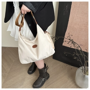 Chic beige nylon crossbody tote bag with a brown leather patch shown on a model