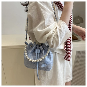 Detail of light blue bucket bag with floral embroidery, pearl handle, and mesh bow