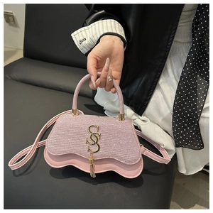 Détail du sac à main en paillettes roses avec logo S doré et décor de pompon tendance