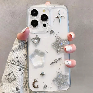 Close-up of glitter stars, moon, and pearl heart charms on a clear iPhone phone case