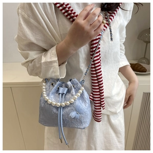 Detail of light blue lace bucket bag with pearl handle and 3D bow decoration