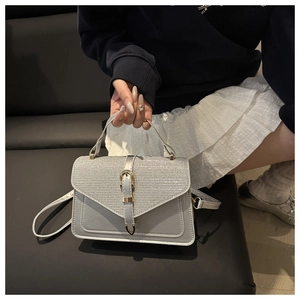 Detail of silver-grey crossbody bag with glitter texture, gold hardware, and top handle
