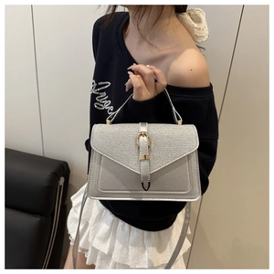 Close-up of silver sequin handbag with metal buckle held by model in casual setting